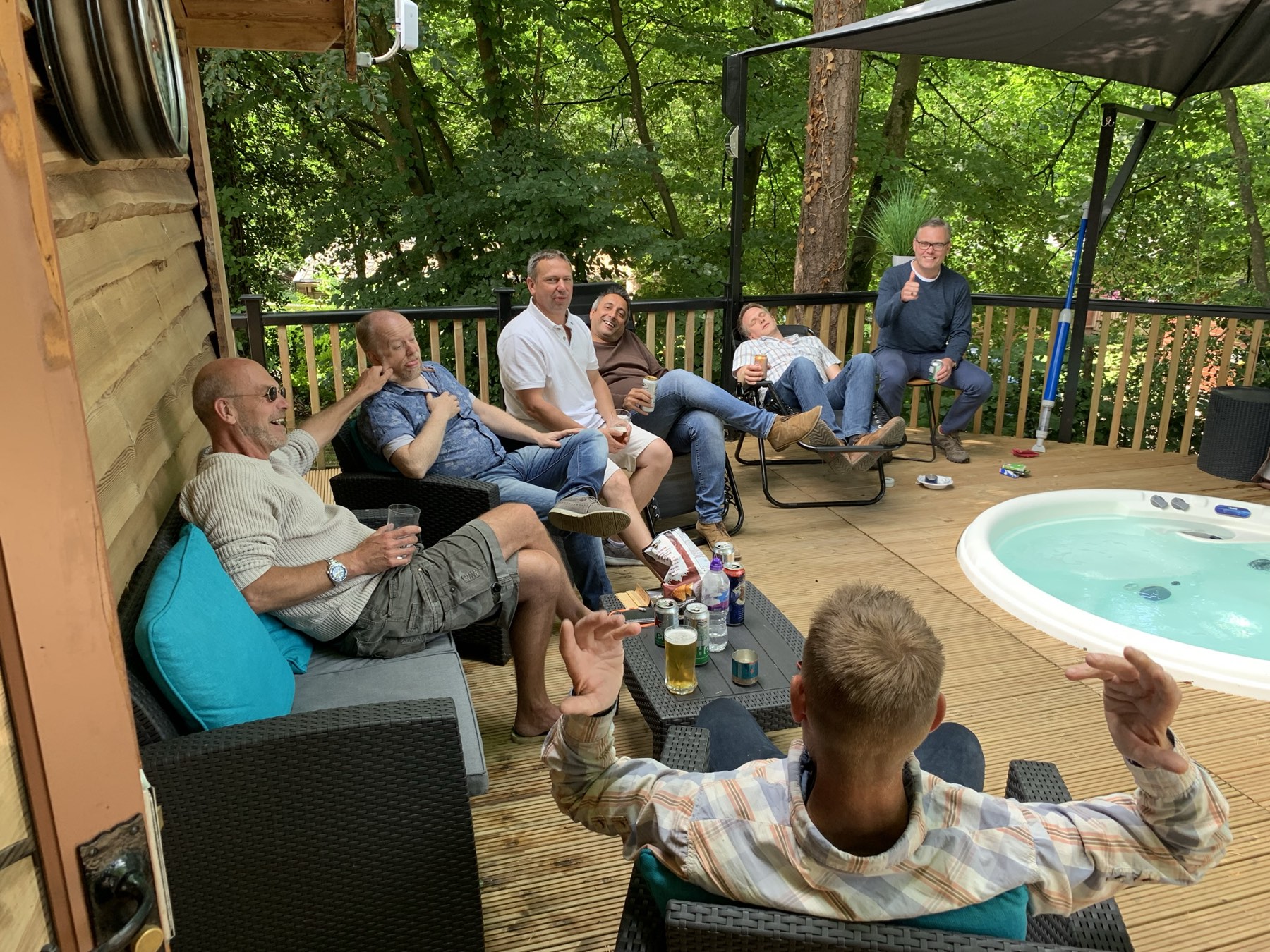 Group relaxing on the deck with the hot tub in summer